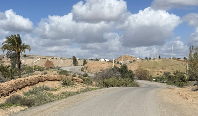 Voyage à moto au Maroc MM6 – En route à travers le piémont de l’Atlas Itinéraire moto à travers le piémont de l’Atlas, avec une route sinueuse, une vallée fluviale, des champs et des montagnes